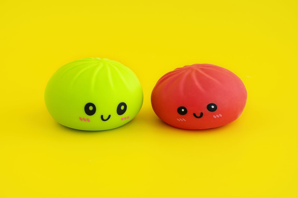 Two soft anti-stress dumpling toys with happy faces on a yellow background
